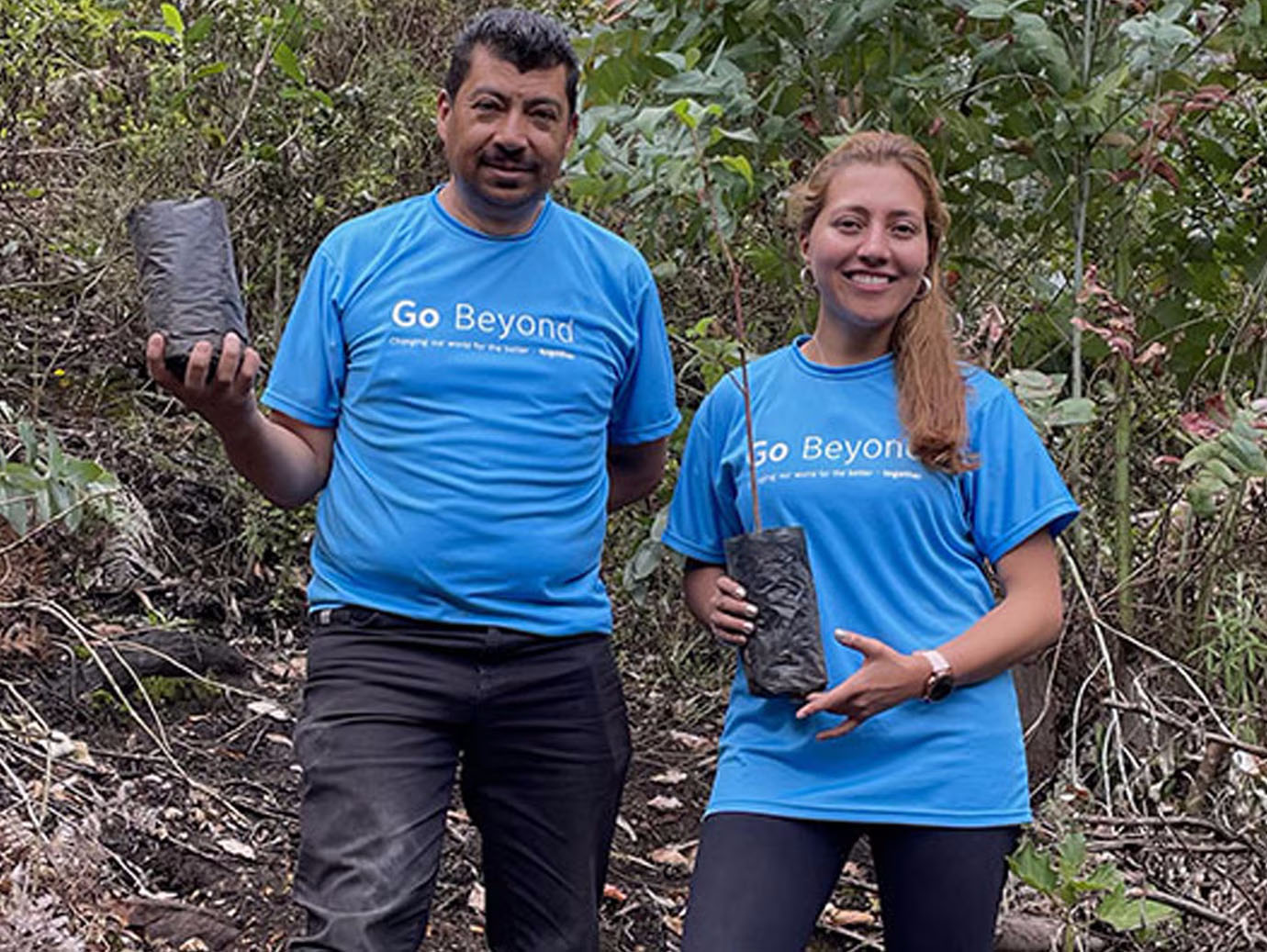 Man and woman smiling and holding plants