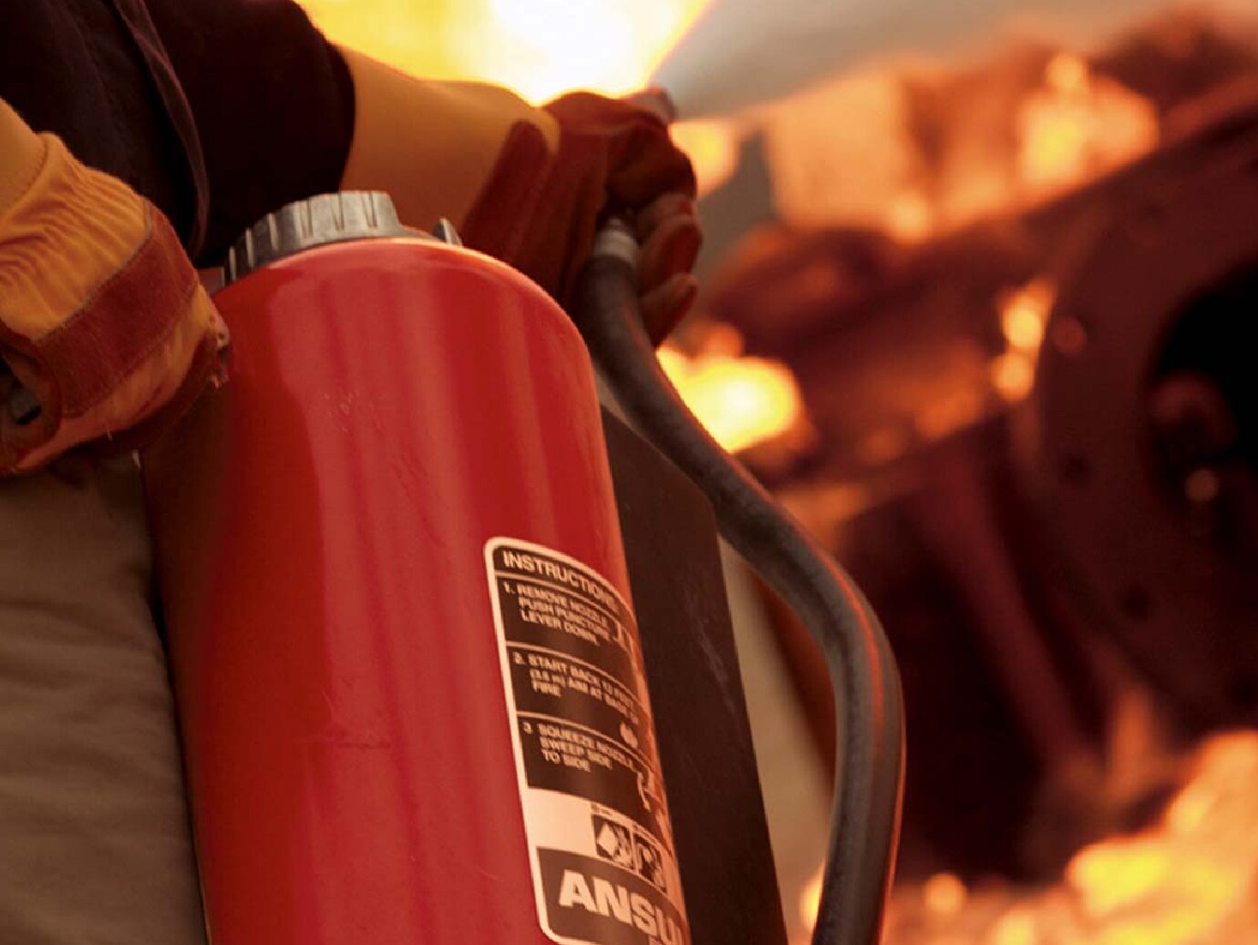 Closeup of firefighter using a fire extinguisher to douse the flames